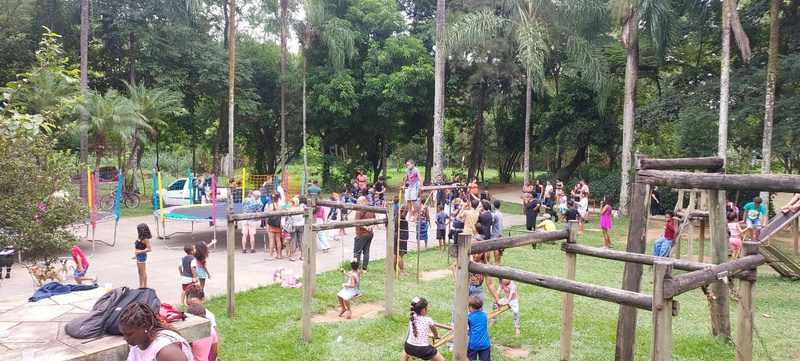 Crianças brincando em praça equipada com playground.
